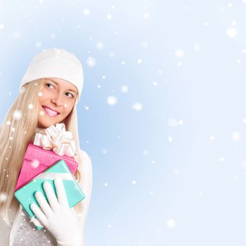 Happy woman holding Christmas gifts, blue background and snow glitter with copyspace, shopping and holidays