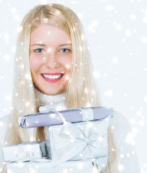 Happy woman holding Christmas gifts, silver background and snow glitter with copyspace, shopping and holidays