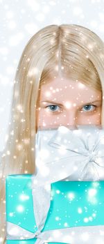 Happy woman holding Christmas gifts, silver background and snow glitter with copyspace, shopping and holidays