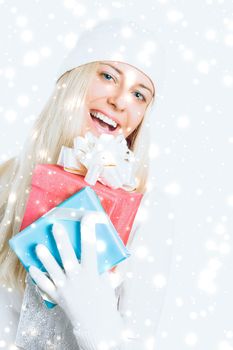 Happy woman holding Christmas gifts, silver background and snow glitter with copyspace, shopping and holidays