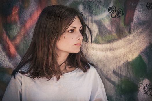 Profile portrait of a teenage girl with long hair on a wall background