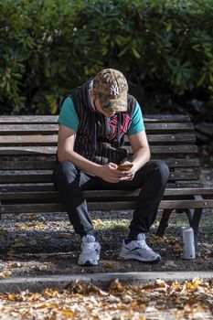 terni,italy october 20 2020:man at the park on a bench who is looking at the phone