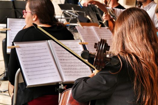 Elche, Alicante- October 20, 2019: Young girl playing the cello in an orchestra on the street in Elche for the fight of breast cancer