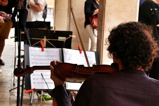Elche, Alicante- October 20, 2019: Young boy playing the violin in an orchestra on the street in Elche for the fight of breast cancer