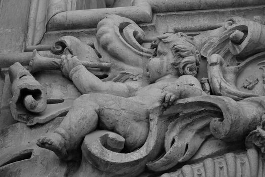 Elche, Alicante, Spain- July 20,2020: Beautiful Carved stone angel playing the trumpet on the main facade of Santa Maria church in Elche, Alicante, Spain.