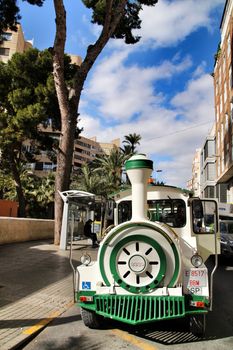 Elche, Alicante, Spain- February 14, 2019: Guided tour on Tourist train through the streets and palm groves in winter under blue sky