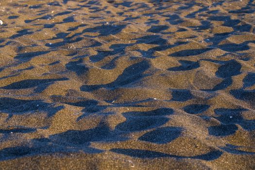 Sea sand background and texture. lights and shadows on the sand. Wallpaper of sand in Georgian Black sea.