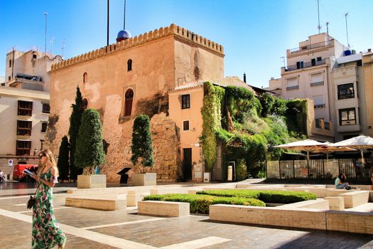Elche, Alicante, Spain- May 30, 2019: Tourist visiting Calahorra Tower with its wonderful vertical garden under blue sky in the center of town in Elche, Alicante, Spain