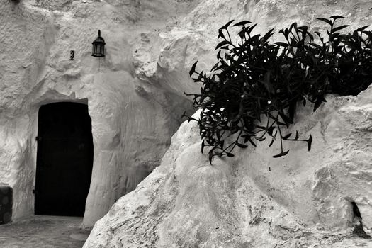 Rojales, Alicante, Spain- September 6, 2020: Facade of white cave house with hanging plant excavated in the mountain in Rojales, Alicante, Spain.