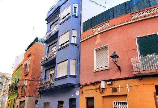Elche, Alicante, Spain- September 9, 2020: Old colorful painted facades with vintage streetlight in Elche, Alicante, Spain. El Raval neighborhood.