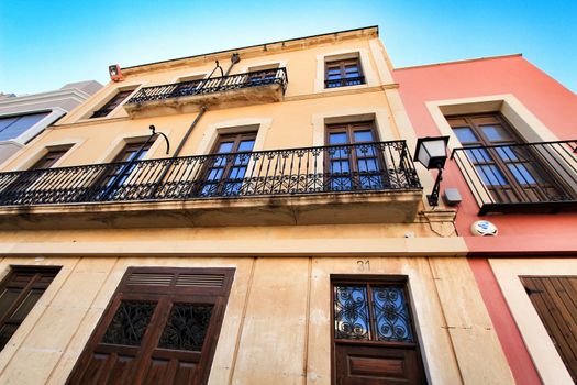 Elche, Alicante, Spain- September 9, 2020: Old colorful painted facades with vintage streetlight in Elche, Alicante, Spain. El Raval neighborhood.
