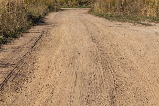 dusty dry dirt road with wild grass thickets on its sidea - T-junction