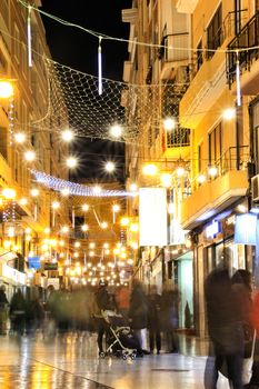 Elche, Alicante, Spain- December 11, 2019: People enjoying and walking at night through the beautiful streets of Elche decorated with lighting and Christmas motifs
