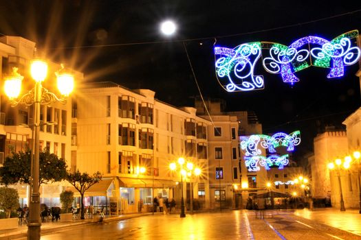 Elche, Alicante, Spain- December 11, 2019: People enjoying and walking at night through the beautiful streets of Elche decorated with lighting and Christmas motifs