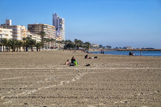 Santa Pola, Alicante, Spain- December 6, 2018: People enjoying and relaxing a sunny day of winter on the beach in Santa Pola, Spain.