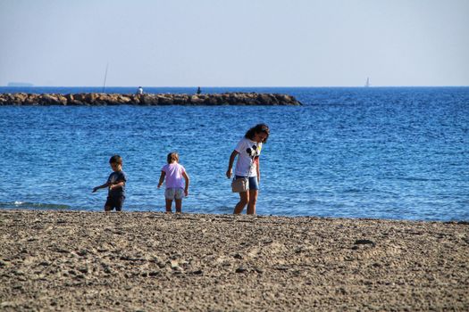 Santa Pola, Alicante, Spain- December 6, 2018: People enjoying and relaxing a sunny day of winter on the beach in Santa Pola, Spain.