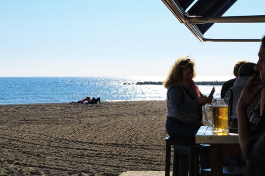 Santa Pola, Alicante, Spain- December 6, 2018: People enjoying and relaxing a sunny day of winter on the beach in Santa Pola, Spain.
