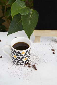 Hot coffee, coffee beans and empty black board on the white background and plant background, studio shoot. Ready to drink. stile life.