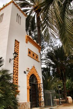 Elche, Alicante, Spain- February 19, 2019: Tourist Office surrounded by palm trees in the municipal park of Elche, Alicante province, Spain
