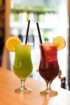 Colorful cocktail with alcohol, juice, lemon and Ice cube in glass On the bar table.