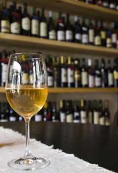 Full white wine glass on the table, wine bottle background, wine magazine and shop in restaurant and bar. Georgian wine in Tbilisi.