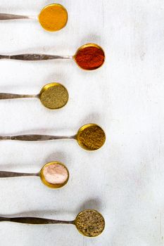 variation of spices on the vintage silver spoons, all spices on the table, colorful food background