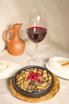 Kuchmachi, Georgian traditional food with meat, walnuts, pomegranates and onion, near red wine and ghomi with cheese.