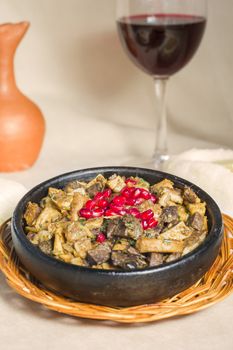 Kuchmachi, Georgian traditional food with meat, walnuts, pomegranates and onion, near red wine and ghomi with cheese.