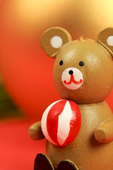 Wooden teddy bear with Christmas decoration on red background