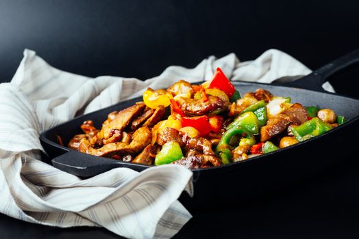 Fried mix of meat and vegetables in cast iron pan