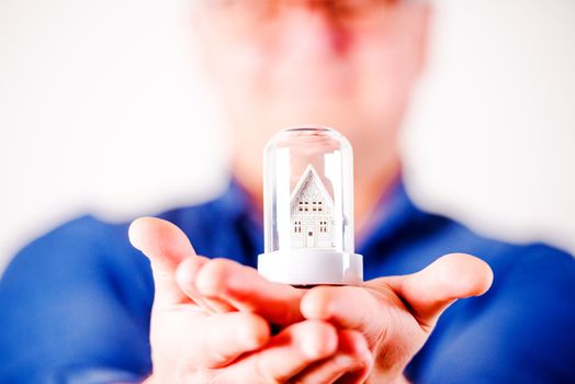 middle aged men in glasses with toy house and  blue shirt