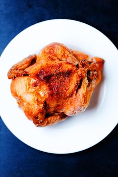 Whole oven roasted chicken on white plate