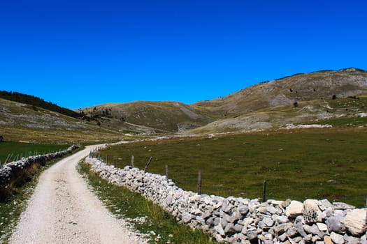 A mountain road surrounded by rocks. Mountain hills in the background. Bjelasnica Mountain, Bosnia and Herzegovina.