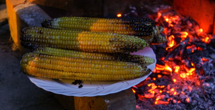 Banner with a plate of roasted corn with grills in the background in the fireplace. Zavidovici, Bosnia and Herzegovina.
