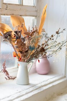 Arrangement of dried flowers in a white ceramic vase. Vintage interior element.