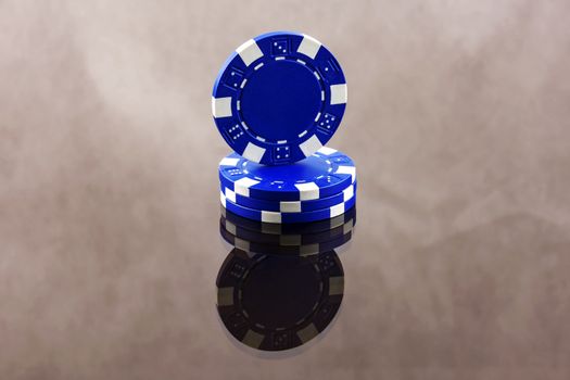 Blue casino chips close-up are reflected in a mirror surface