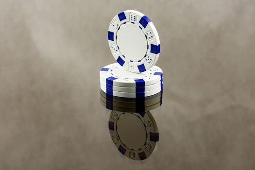 White casino chips close-up are reflected in a mirror surface