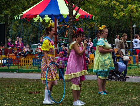 On the green grass in the park are three women dressed in clown costumes