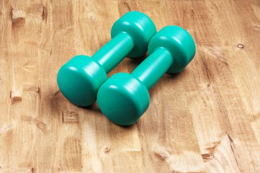 On the wooden surface are two dumbbells for sports