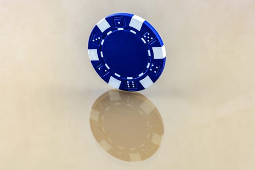 On the reflective surface is a blue casino chip