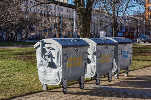 On the city street there are containers for separate collection of secondary raw materials, garbage