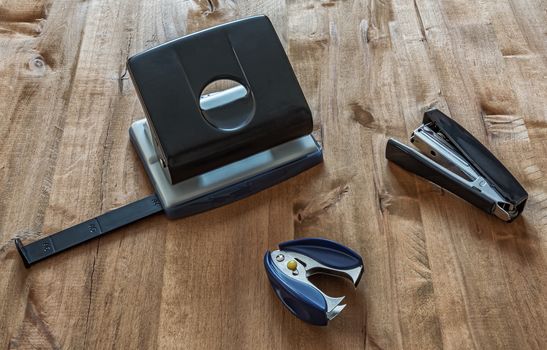 On the wooden surface are a stapler, anti-stapler and puncher