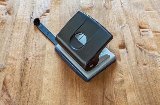 On a wooden table, a hole punch for punching holes in a paper