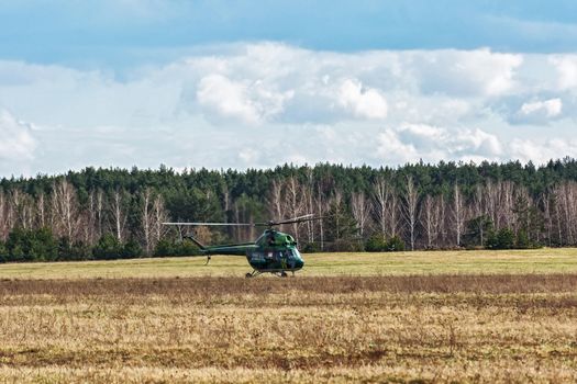 Belarus, Minsk - 15.04.2017: MI-2 helicopter landed on the field near the forest belt