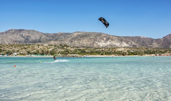 Kitesurfer athlete at speed slides over the water surface