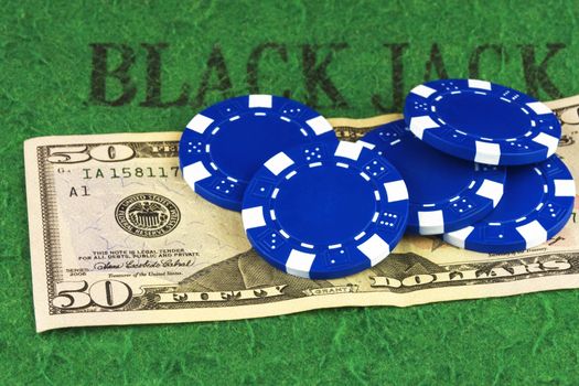 On the green cloth of the poker table is a bill of $ 50 and five blue chips