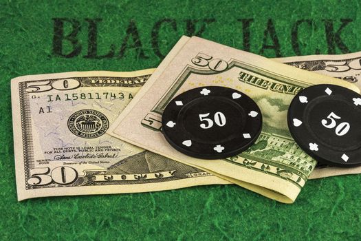 On the green cloth of the poker table there are two banknotes of $ 50 and two black chips