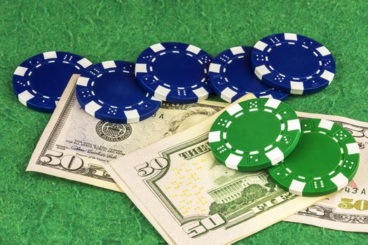 On the green cloth of the poker table are two bills of $ 50, green and blue chips