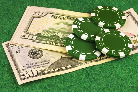 On the green cloth of the poker table is a bill of $ 50 and four green chips