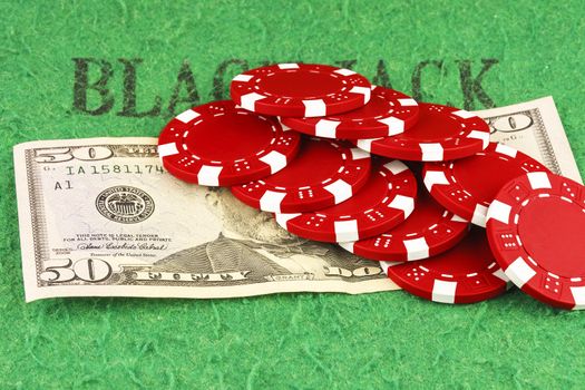 On the green cloth of the poker table is a bill of $ 50 and ten red chips